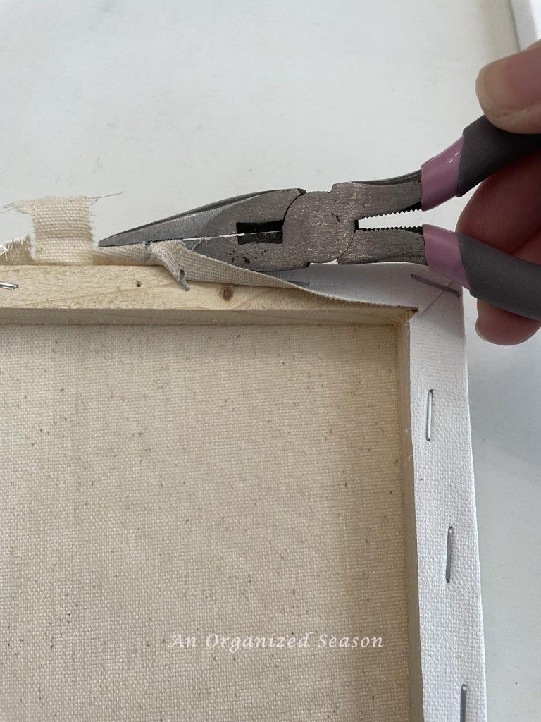 Use a pair of pliers to remove the canvas from a frame. 