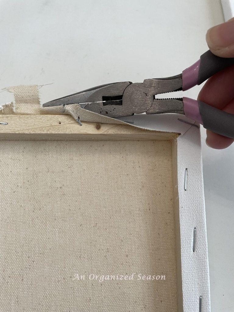 Use a pair of pliers to remove the canvas from a frame.