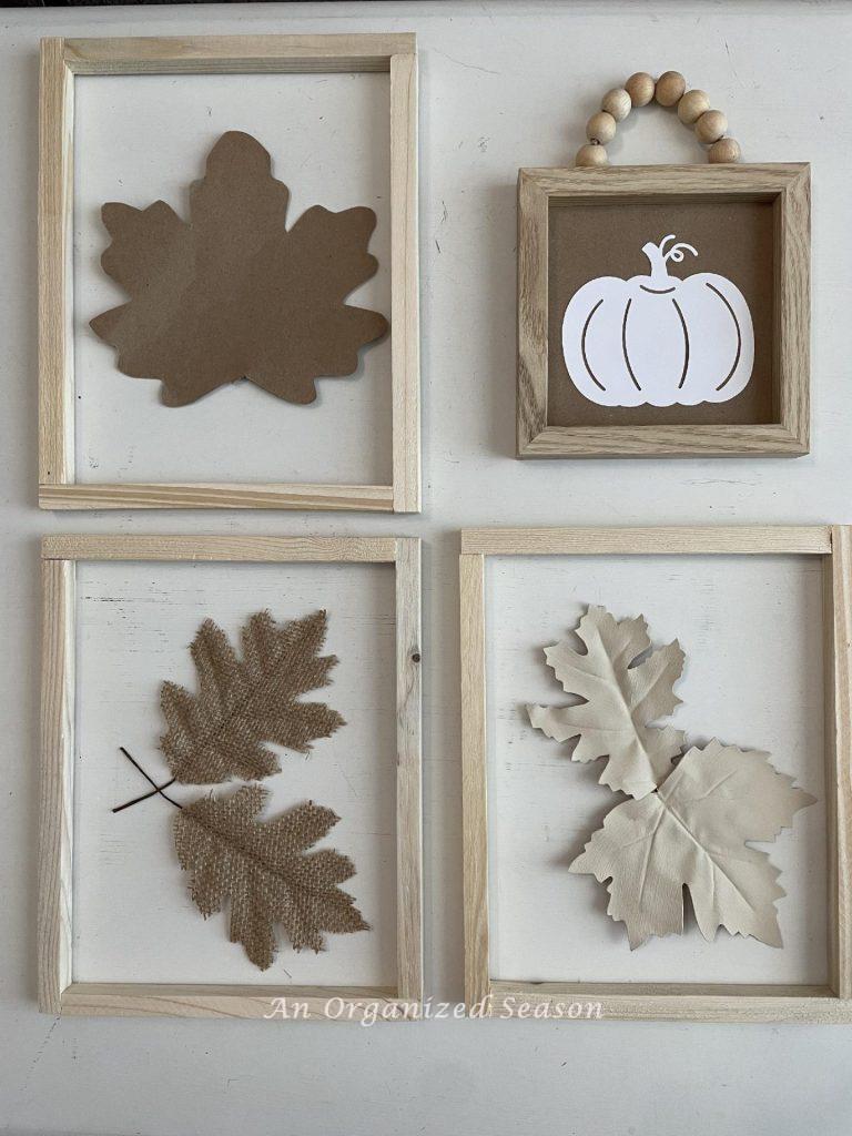 Neutral leaves and a pumpkin inside wood picture frames.