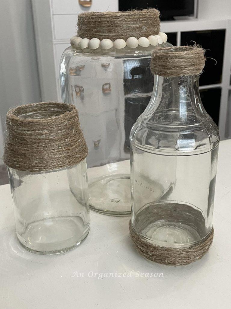 Three glass jars decorated with twine and wood beads. 