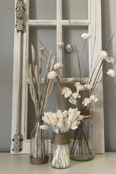 Three glass vases with white dried flowers.