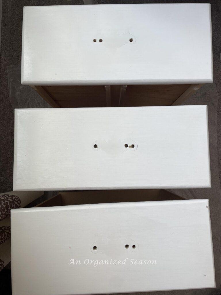 Three dresser drawers with three holes in each one. 