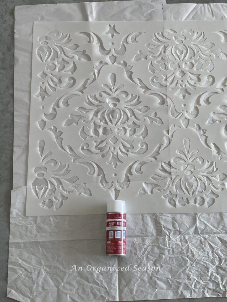 Spray adhesive on the back side of a large stencil. 