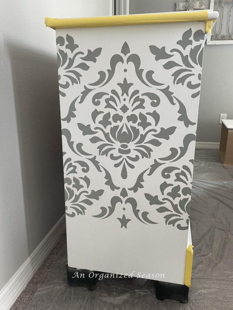 Damask design in gray on a white dresser. 