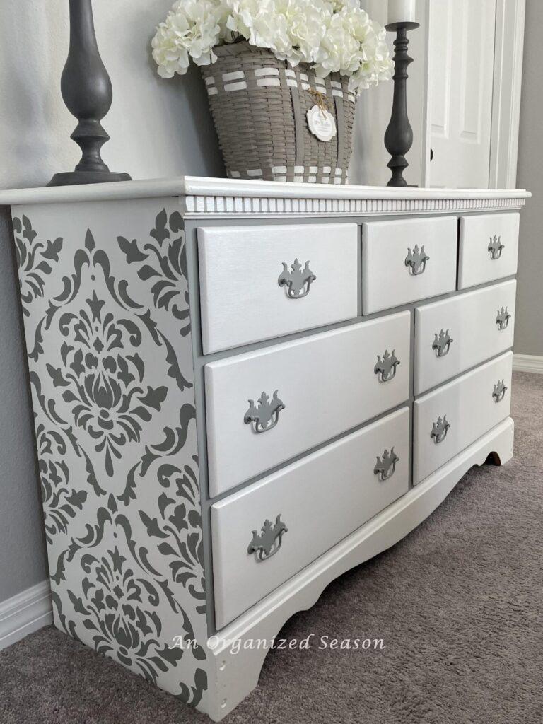 White dresser with a damask stencil design on the sides. 