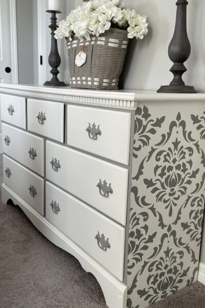 White dresser with a gray damask stencil design on the sides.