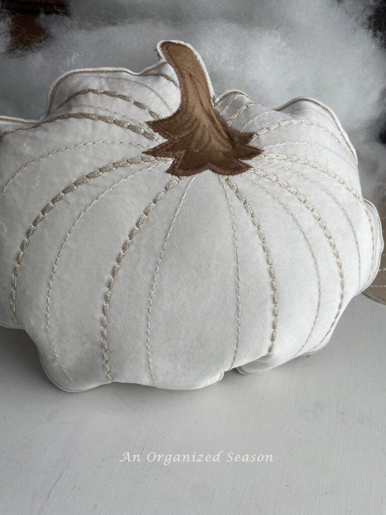 A stuffed pumpkin pillow sitting in front of fiberfill. 