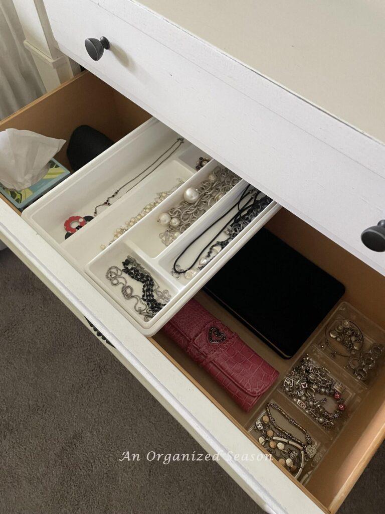 A nightstand drawer with a jewelry organizer in one of the drawers. 