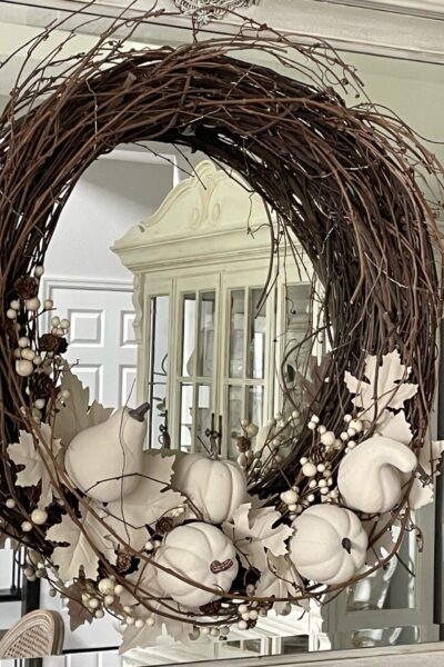 Neutral Fall pumpkin wreath hanging on a mirror.