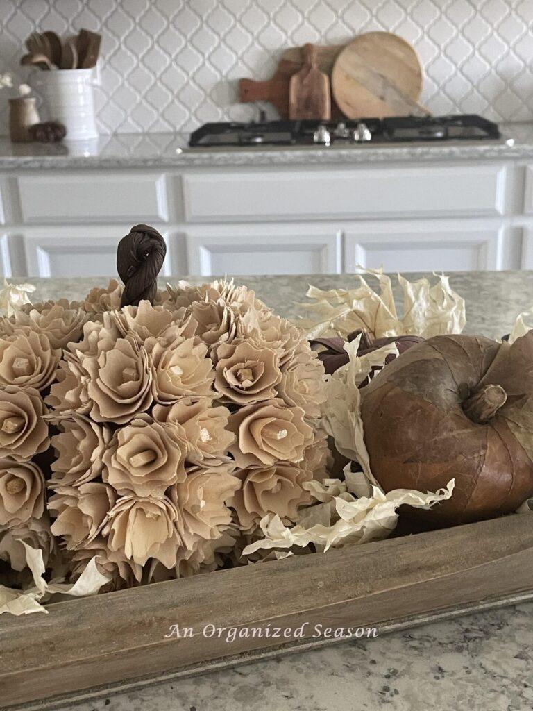 Pumpkin covered with wood flowers and a faux apple. 