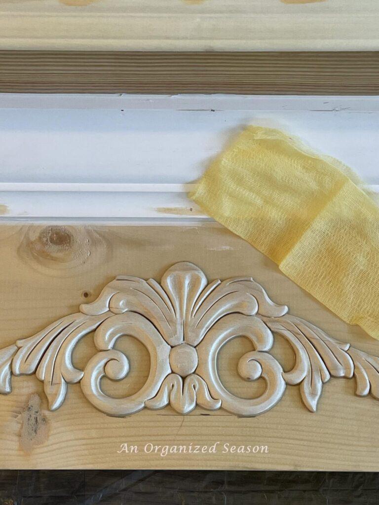 Wood applique and tack cloth laying on a faux fireplace mantel