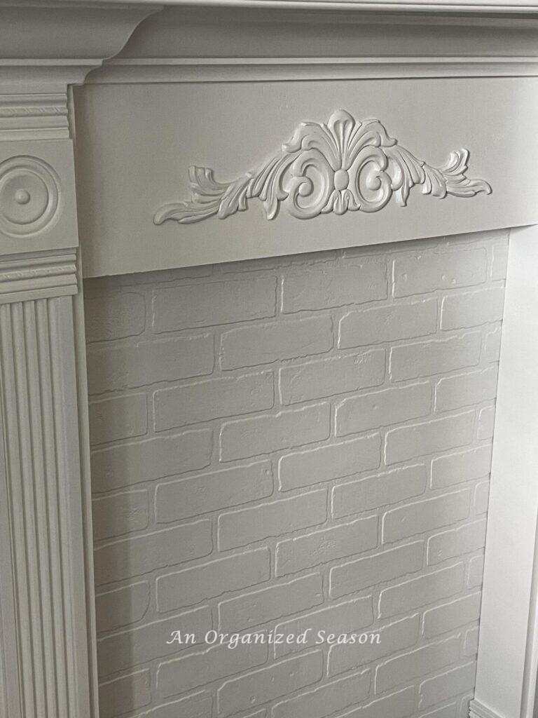 Closeup of trim work on a white Faux fireplace mantel.