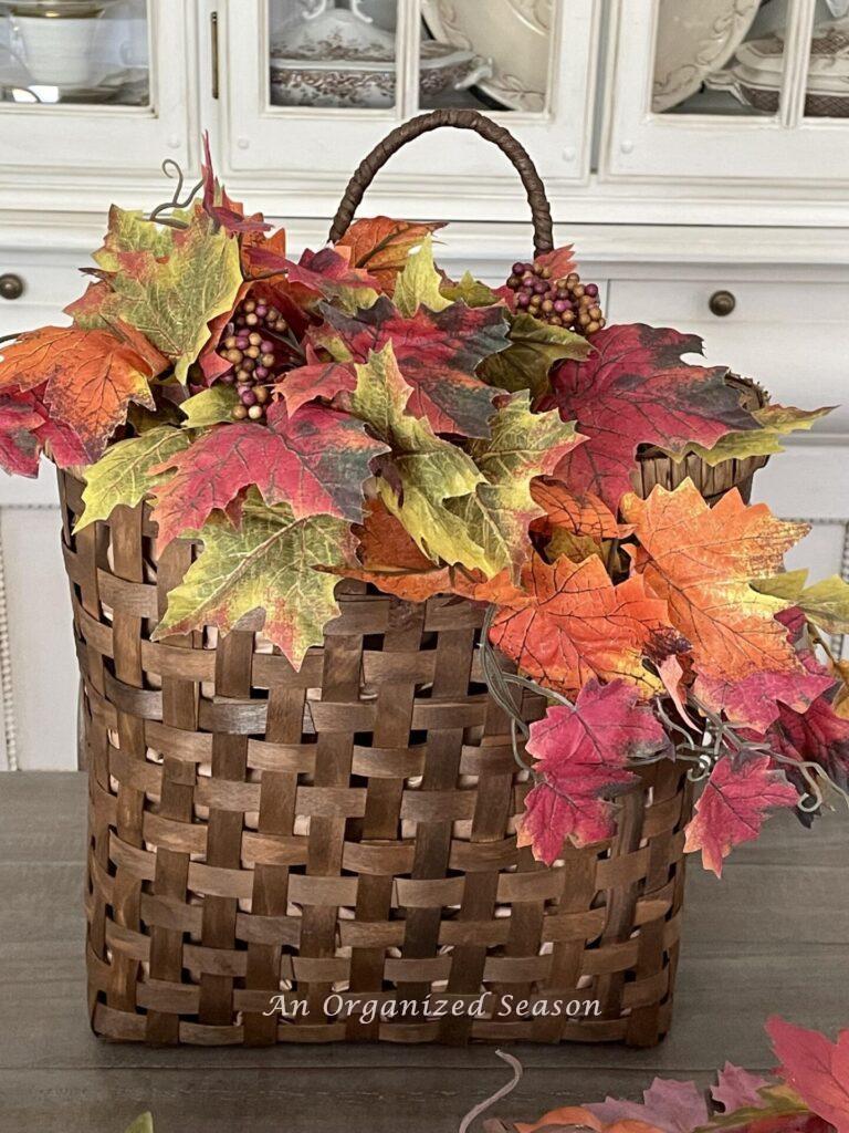 Step two to make a front door fall wreath is to add the leaf stems to the basket. 
