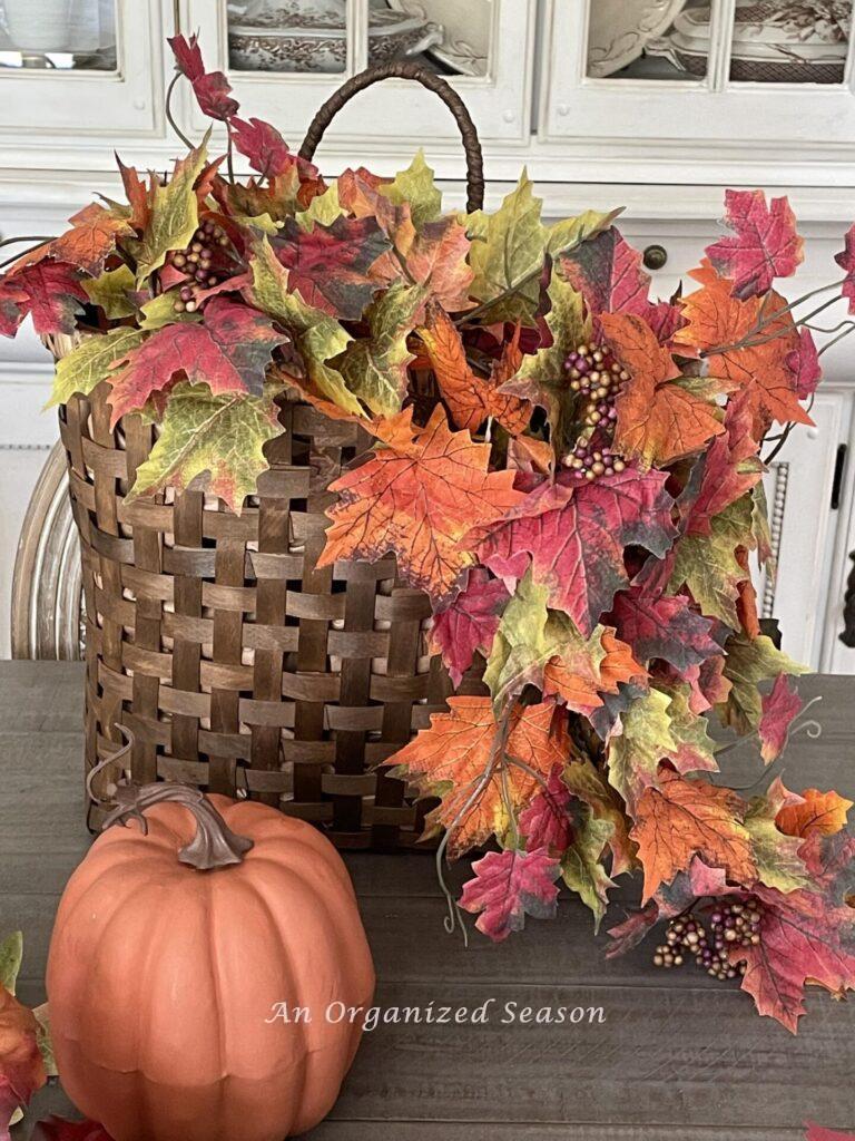 A basket with faux fall leaves draping down the right side. 