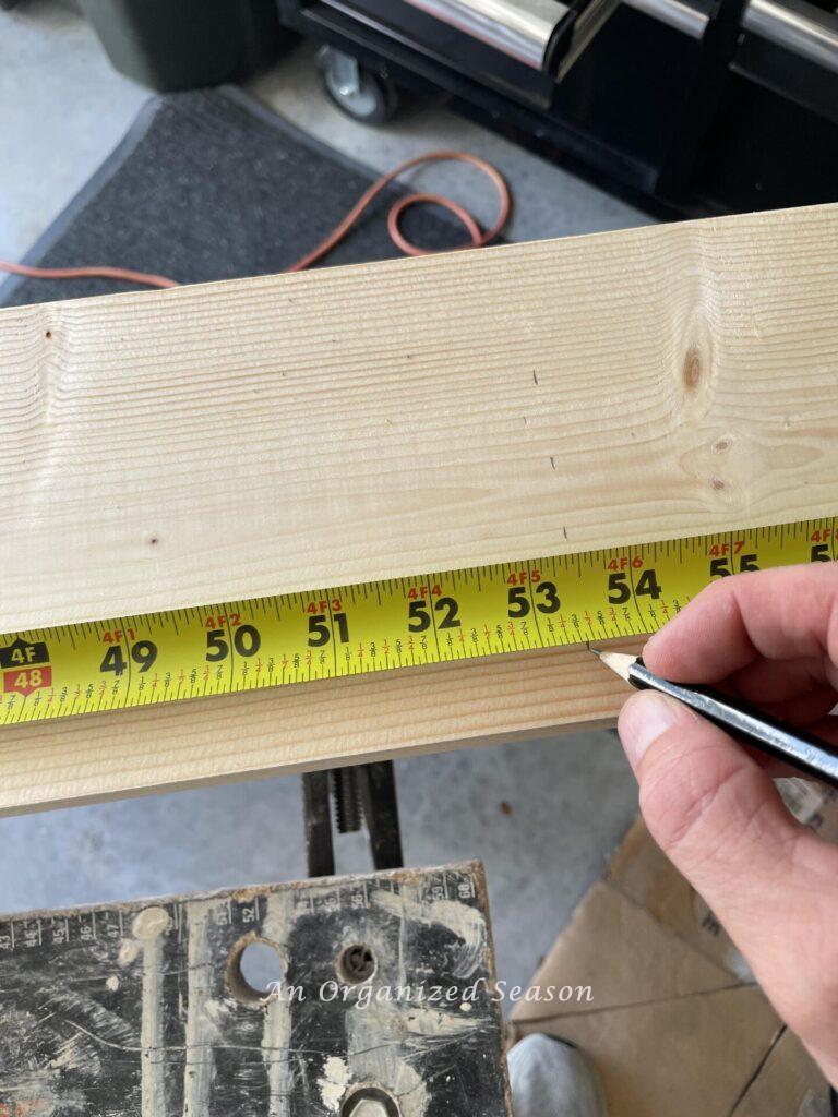 Hand with pencil marking measurement on mantel shelf board