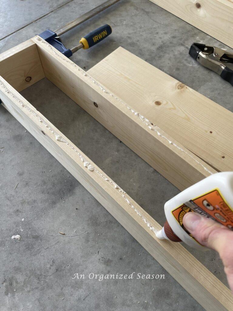 Applying wood glue bead to one by four side boards