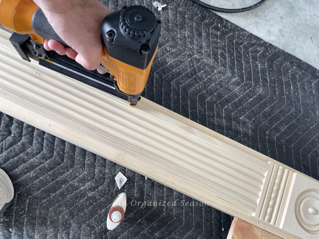 Brad nailing fluted trim to column of mantel