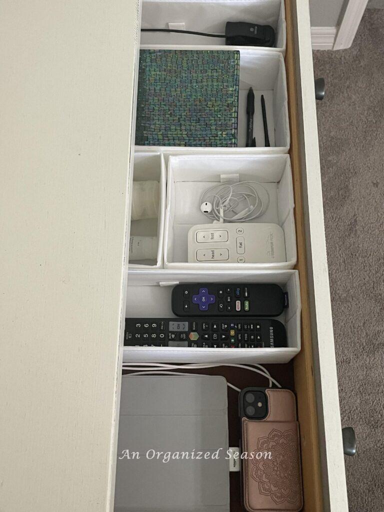 An organized nightstand drawer with white dividers. 