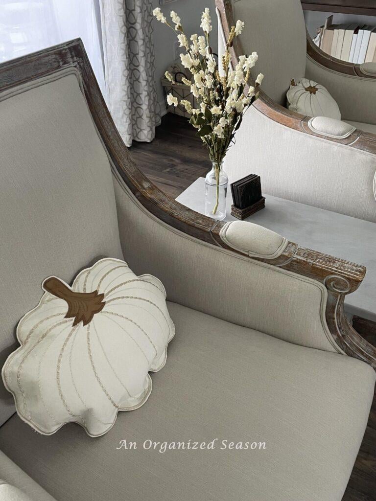 Stuffed pillow pumpkins sitting in two chairs.