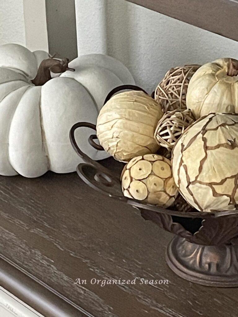 A white pumpkin next to a bowl of fall orbs.