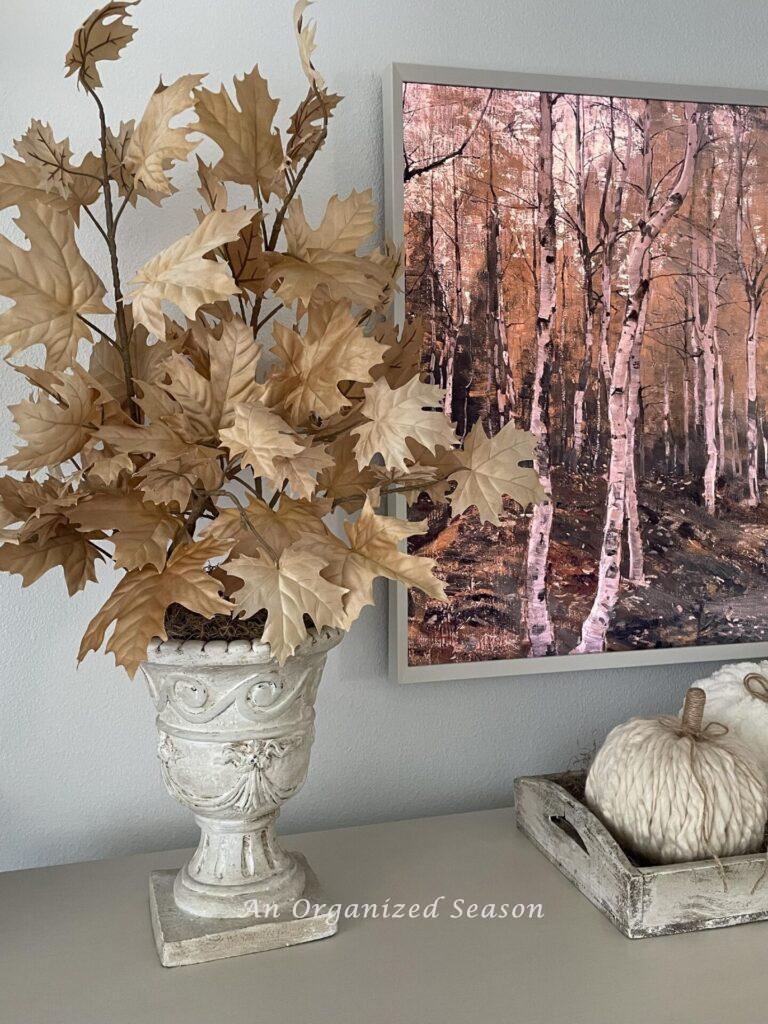 A white vase filled with tan leaf stems. 