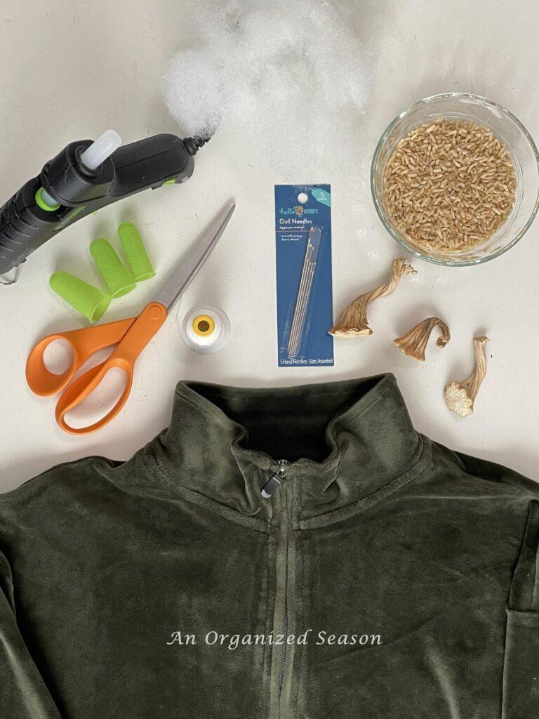 Velvet shirt, scissors, thread, doll needle, glue gun, rice, and three pumpkin stems. 