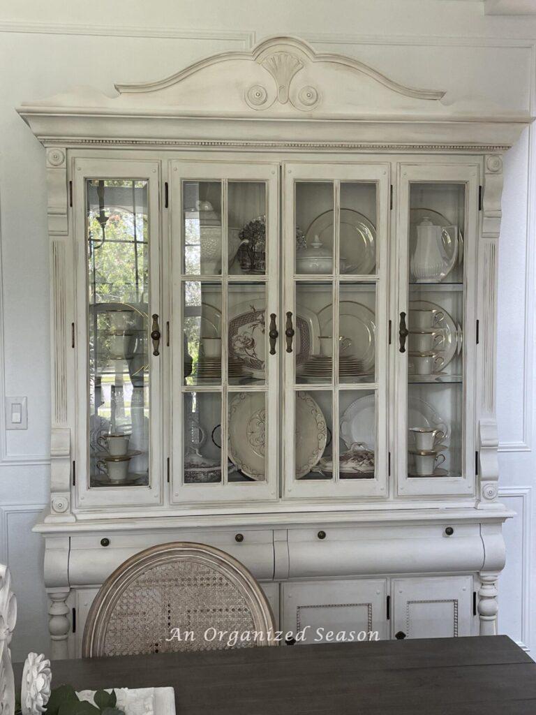 A china cabinet that was painted white and antiqued with brown wax. .