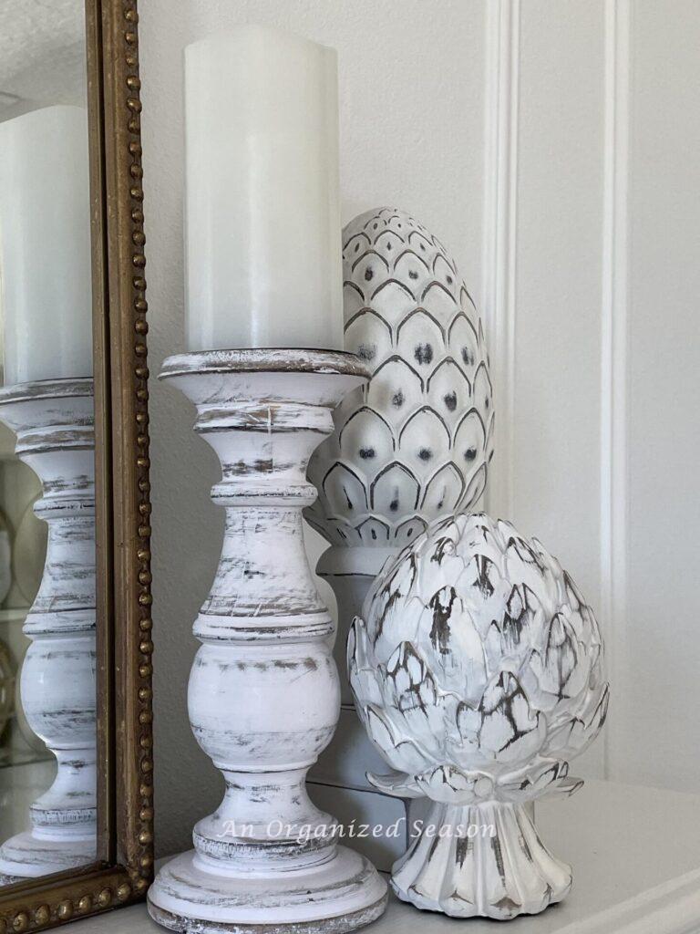 Two white artichoke statues and a candlestick. 