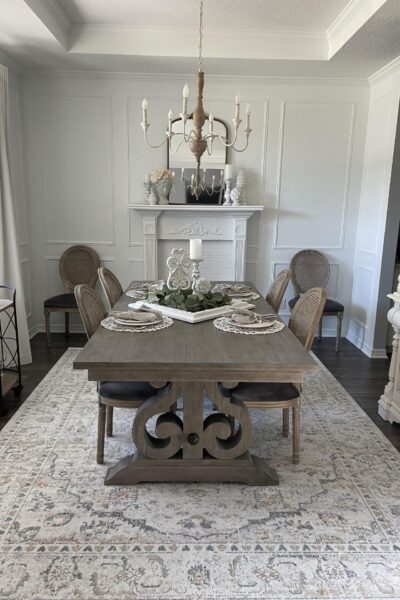 A white dining room with gray table and neutral rug.