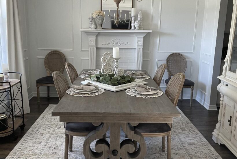 A white dining room with gray table and neutral rug.