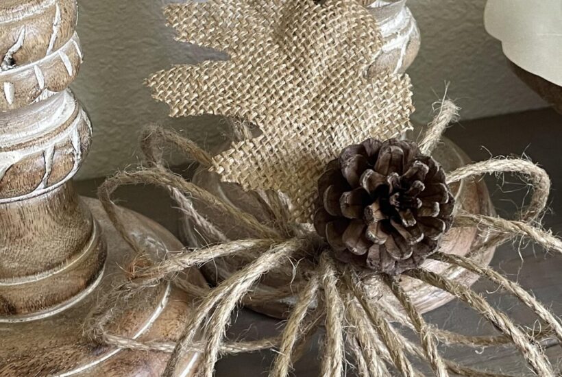 A jute twine pumpkin next to two candlesticks.