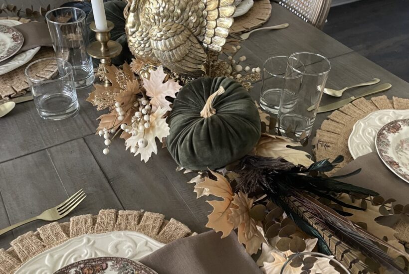 A Thanksgiving table with gold turkey, 2 candlesticks, green velvet pumpkin and organics.