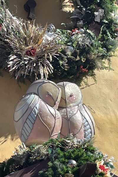 Statues of lovebirds in front of a Christmas wreath