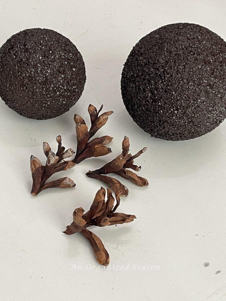 Two styrofoam balls painted brown and the tips of four pinecones. 