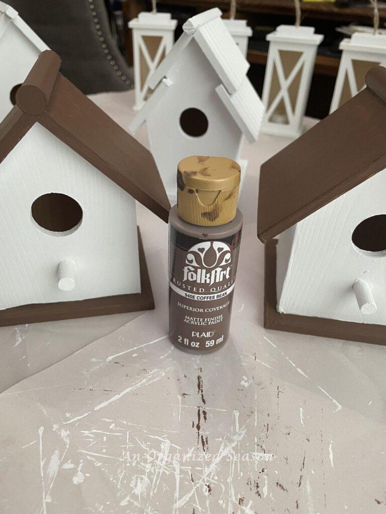 Birdhouses and bottle of brown paint. 