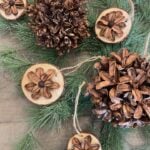 Pinecone and Wood Slice Christmas Ornaments laying on greenery