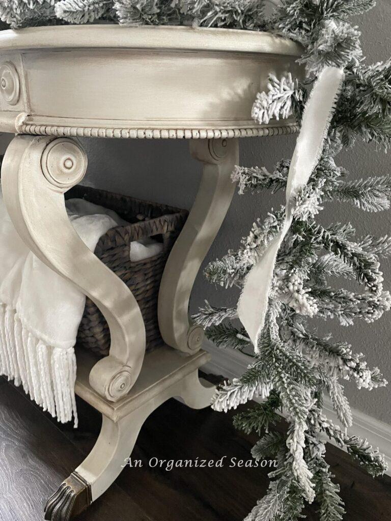 A garland with white ribbon hangs over a console table. 