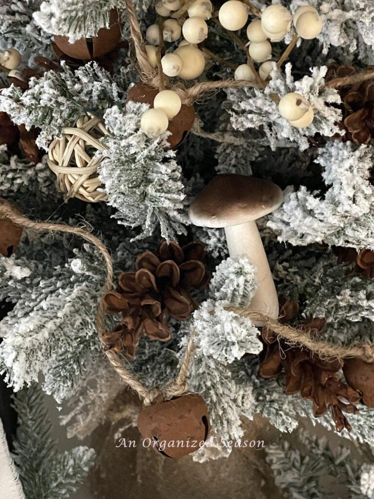 Mushrooms, pinecones, jingle bells, and berry picks decorate a tree. 