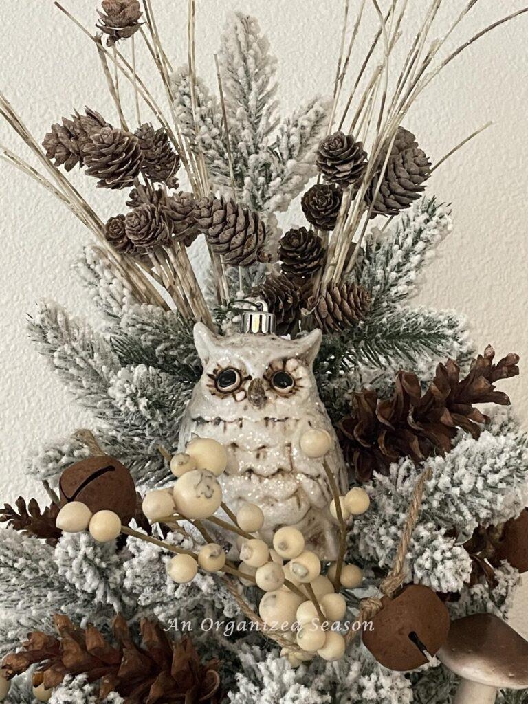 An owl and pinecone picks atop a Christmas tree. 