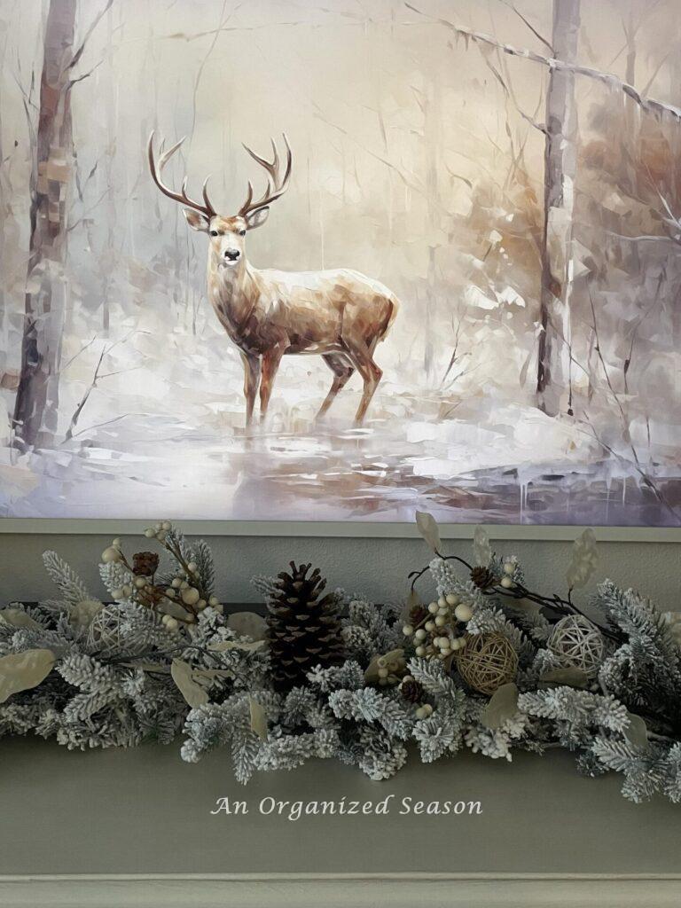 A deer picture hanging over a decorated Christmas garland. 