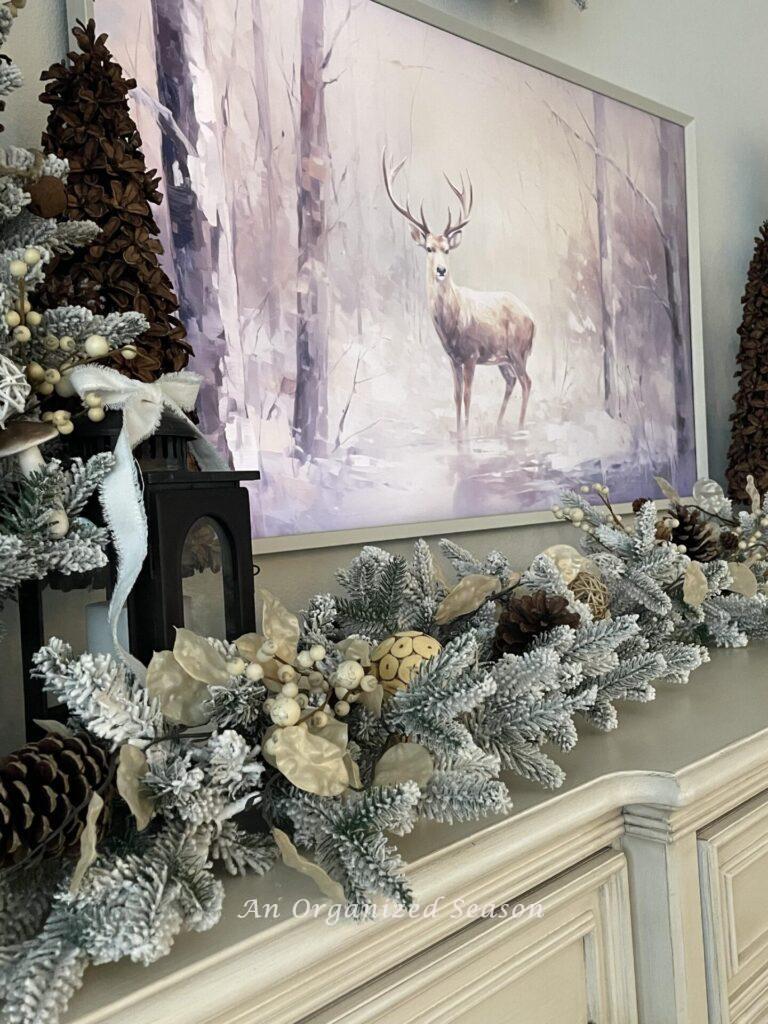 A garland decorated for Christmas laying under a picture of a deer.