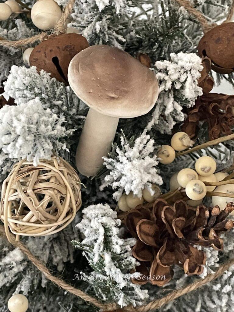 A mushroom, pinecone, dried orb, and brown bells on a Christmas tree. 