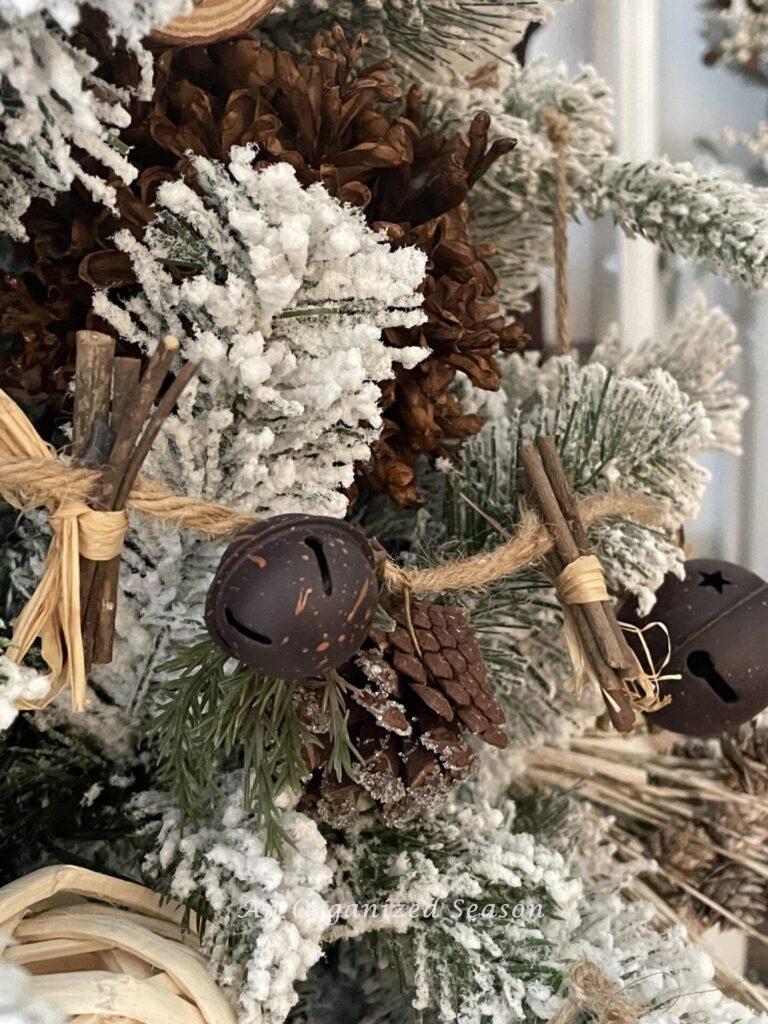 Step two to create a woodland Christmas tree is to add a pinecone, jingle bell, and twig garland around the tree. 