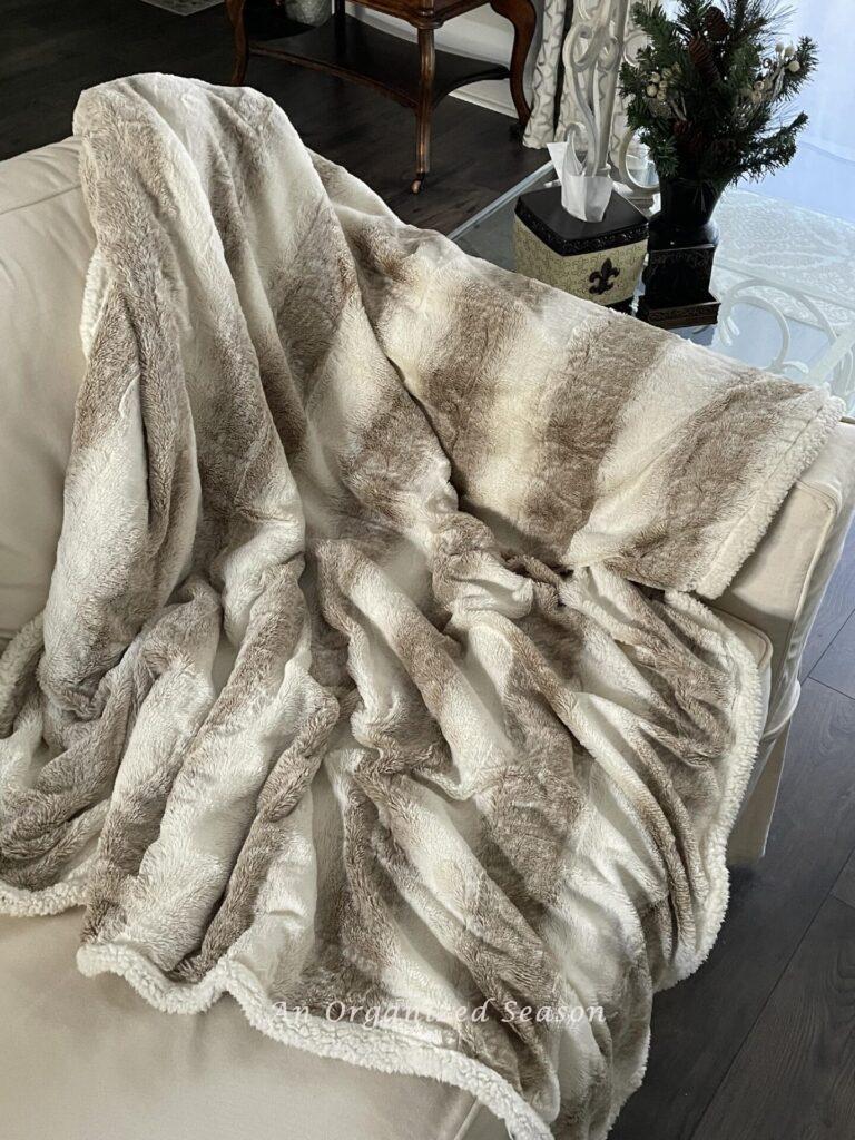 A faux fur throw laying over a couch. 