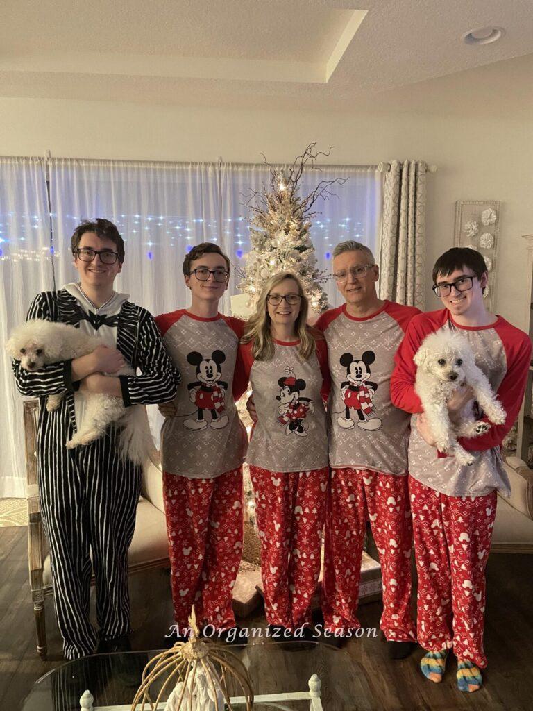 A family wearing matching Mickey Mouse PJs except for one person. 
