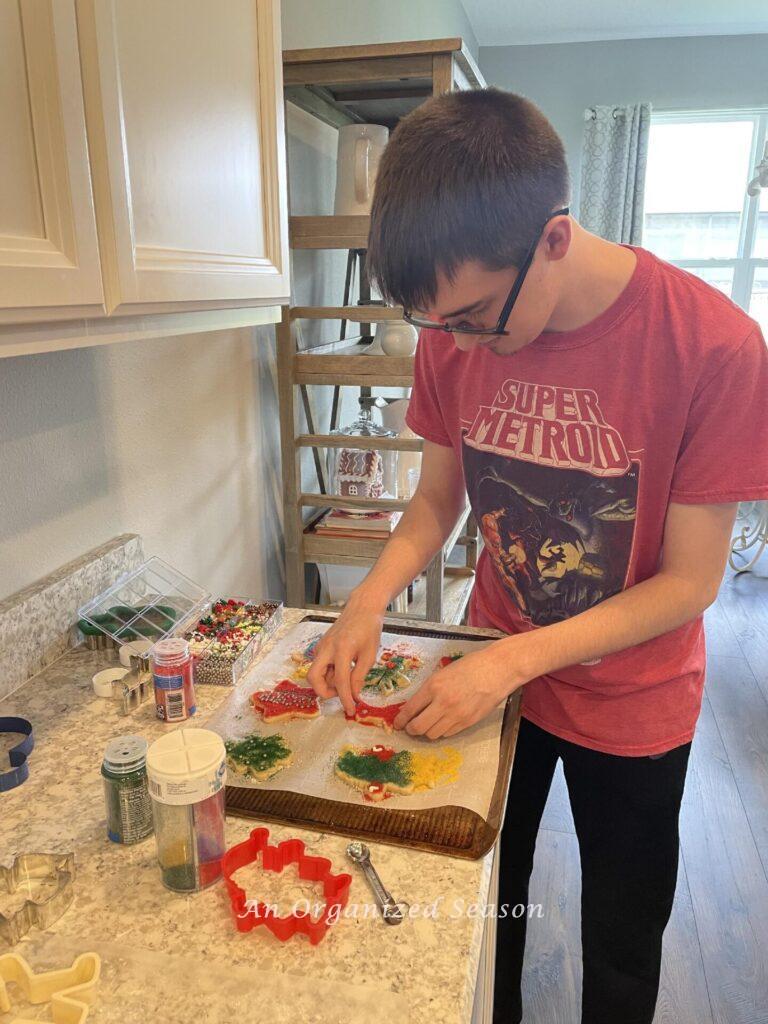 A boy decorating Christmas cookies with colored sugar. 