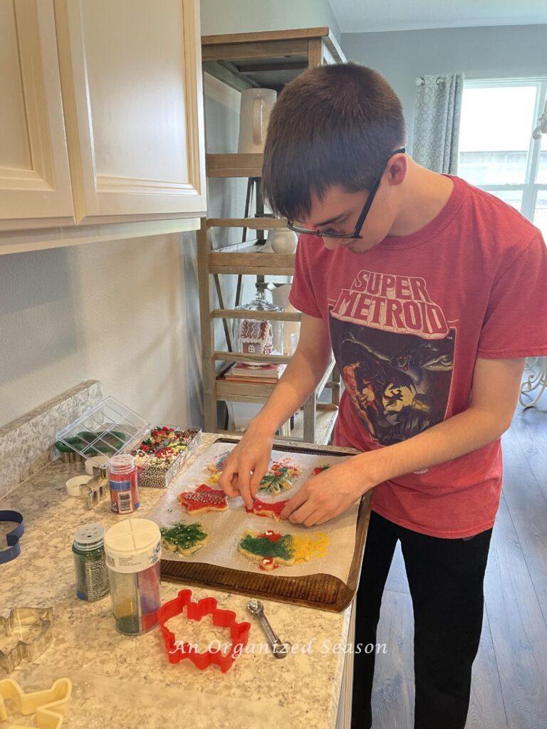 A boy decorating Christmas cookies with colored sugar.