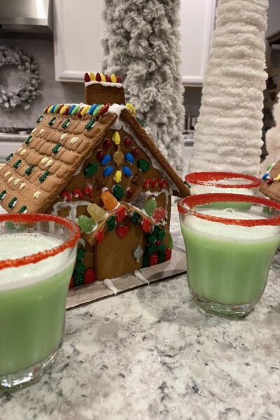 A gingerbread decorated house and cups of Grinch punch