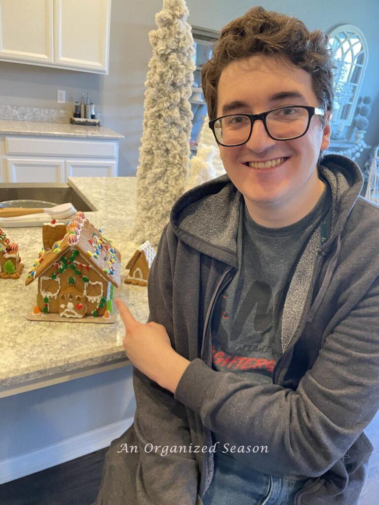 A boy pointing to a gingerbread house. 