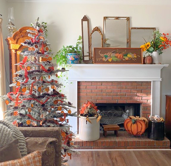 A Christmas tree and mantel decorated for Thanksgiving. 